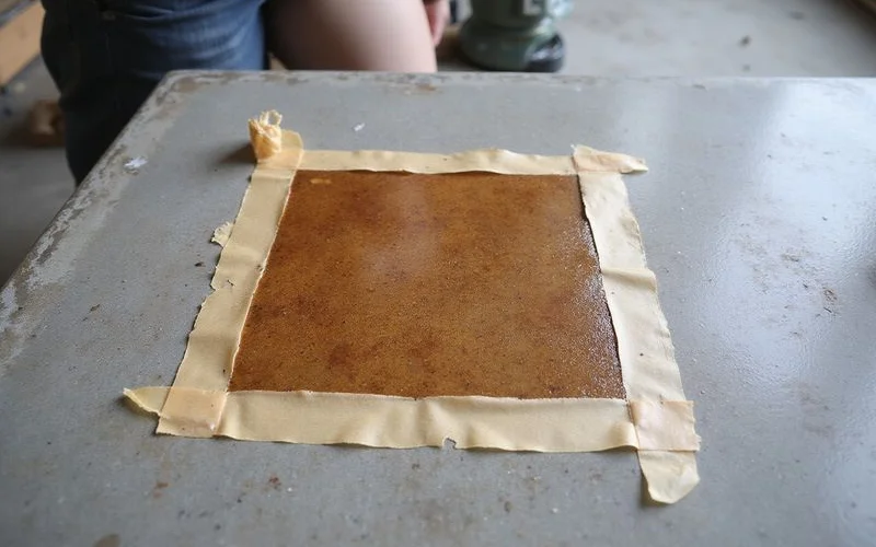 Small stain test patch on a prepared slab beside an untreated area